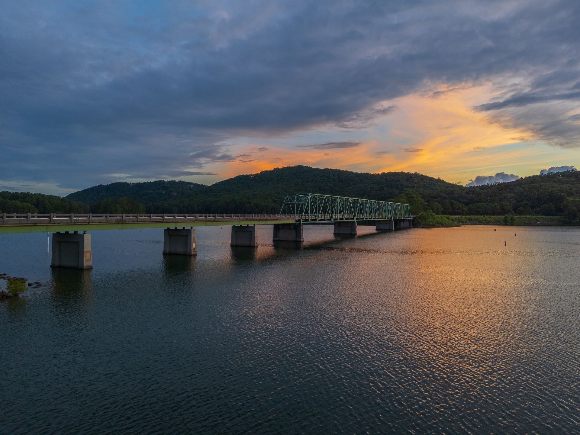 A bridge over a lake Allatoona at Red Top Mountain State Park at sunset with mountains in the background