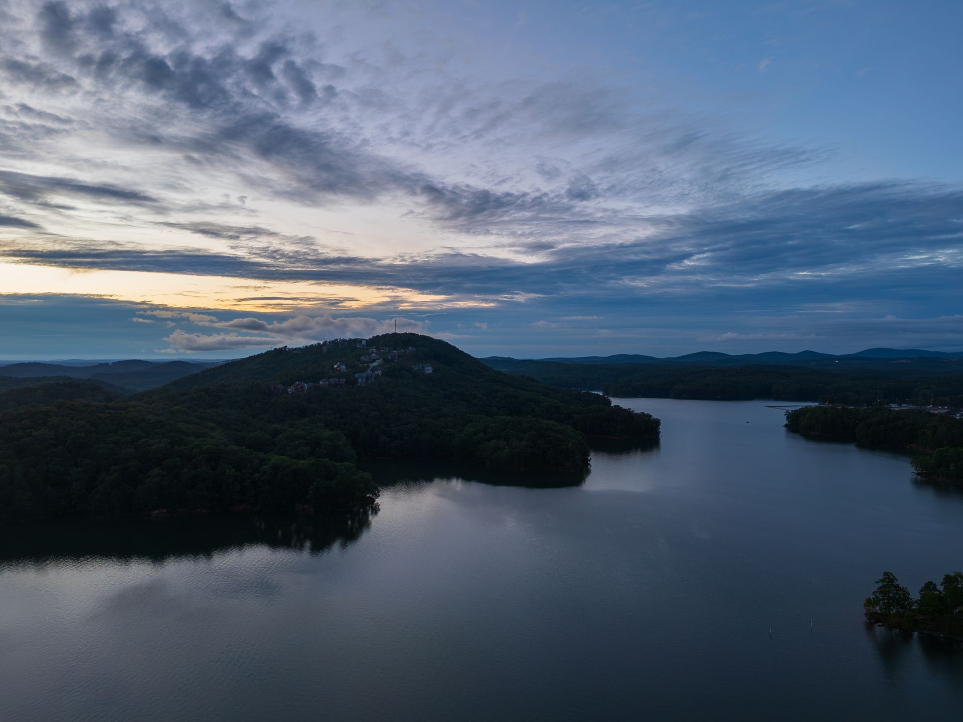 An aerial view of a Lake Allatoona at Red Top Mountain State Park with mountains in the background at sunset.