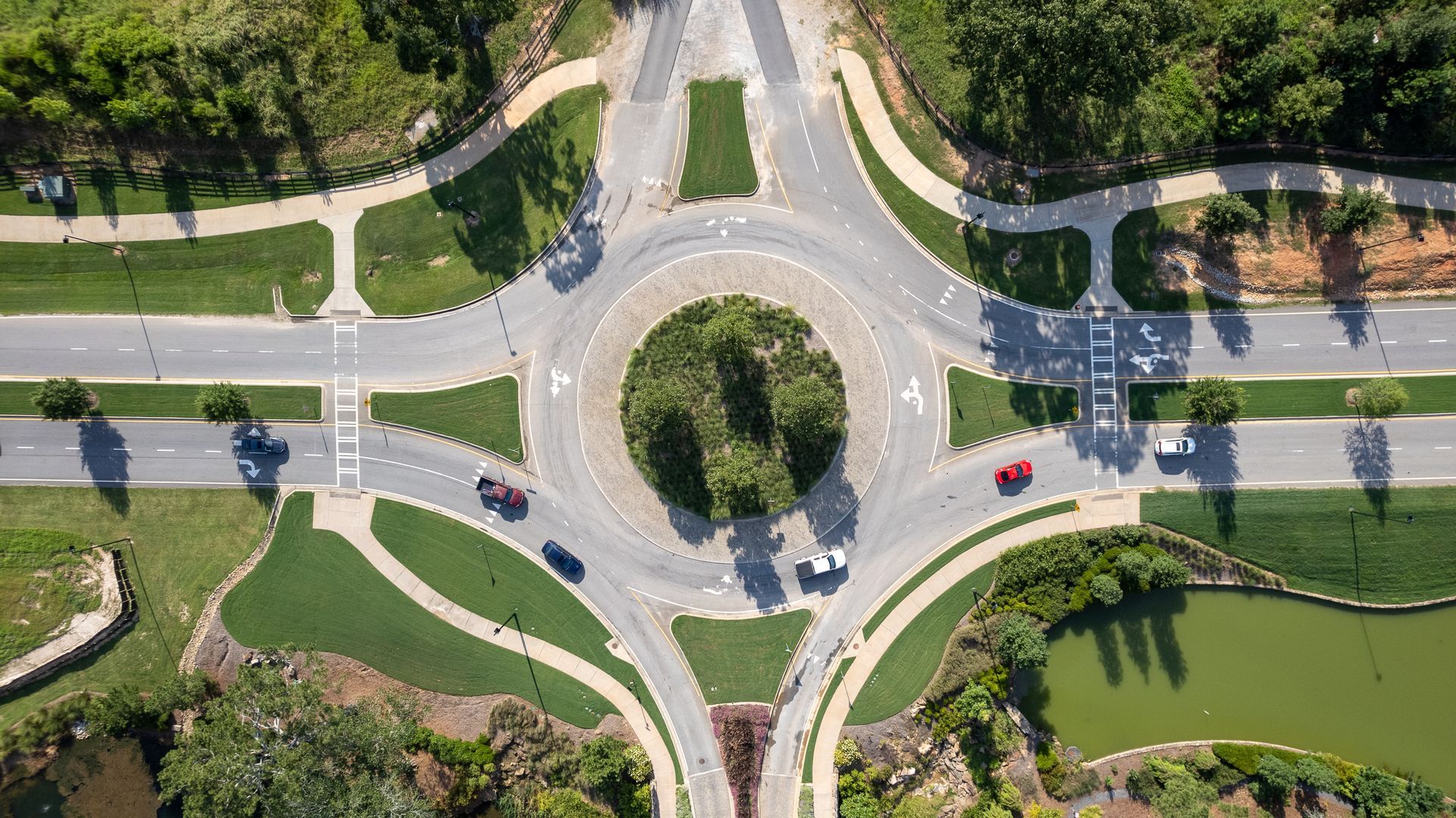 An aerial view of a roundabout with cars driving around it.