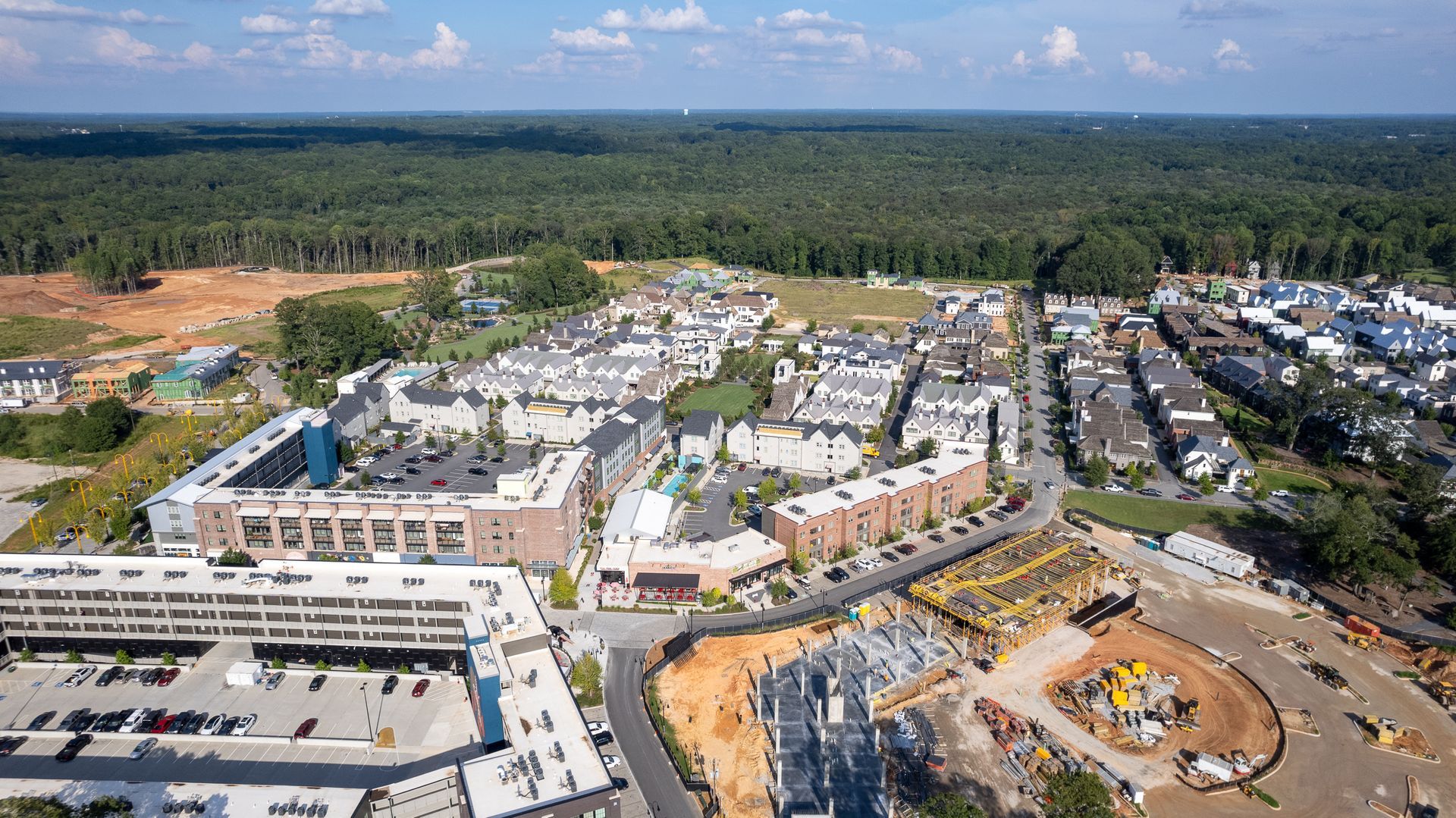An aerial view of a city with a lot of buildings and trees in the background.