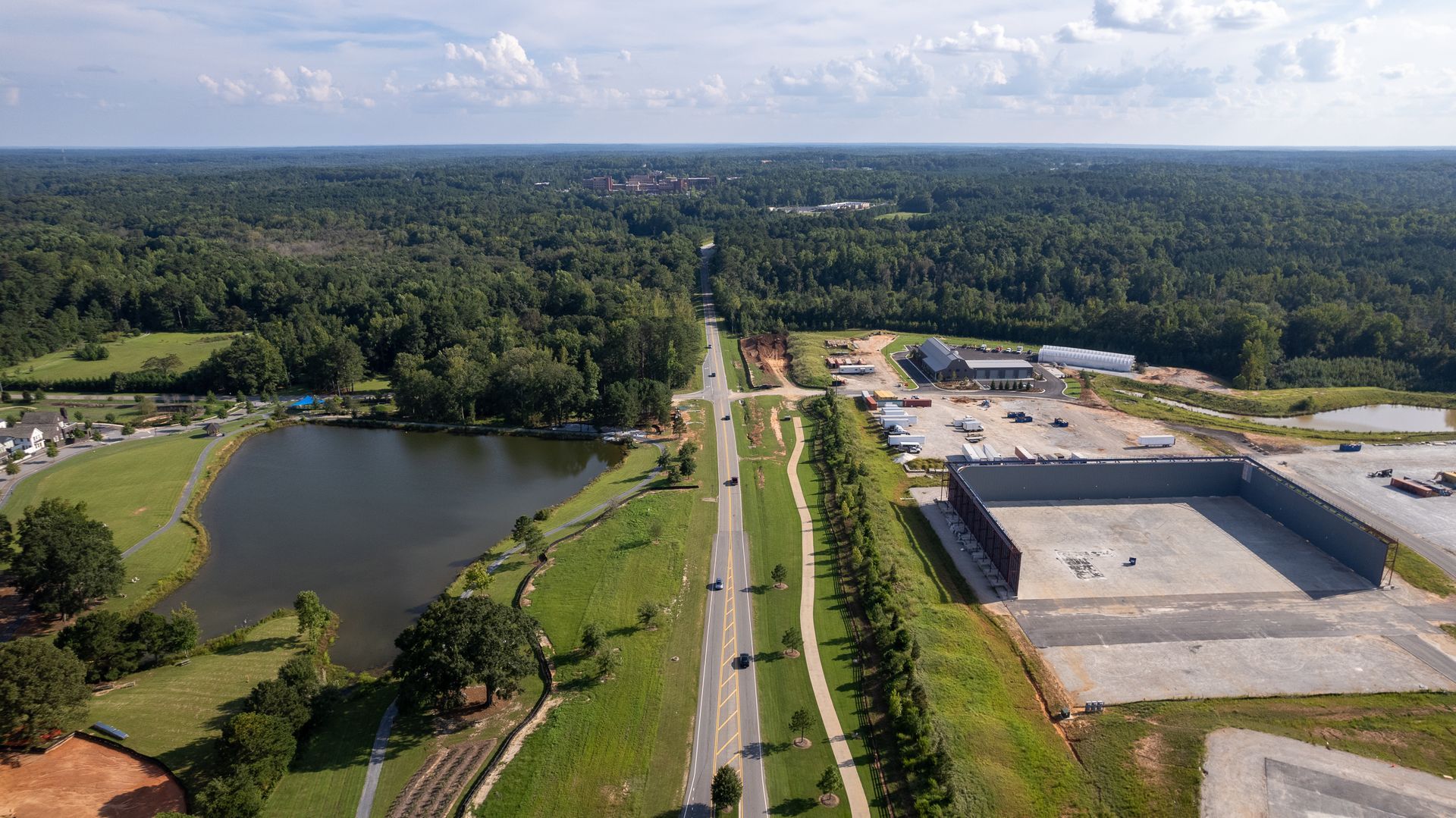 An aerial view of a highway surrounded by trees and a lake.