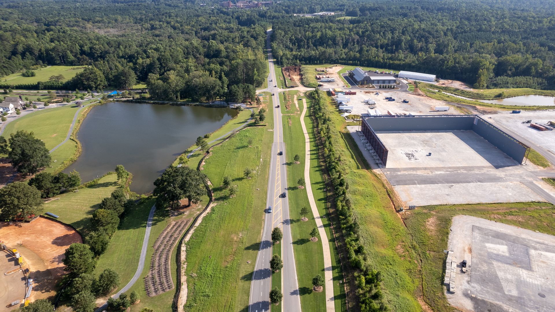 An aerial view of a highway surrounded by trees and a lake.
