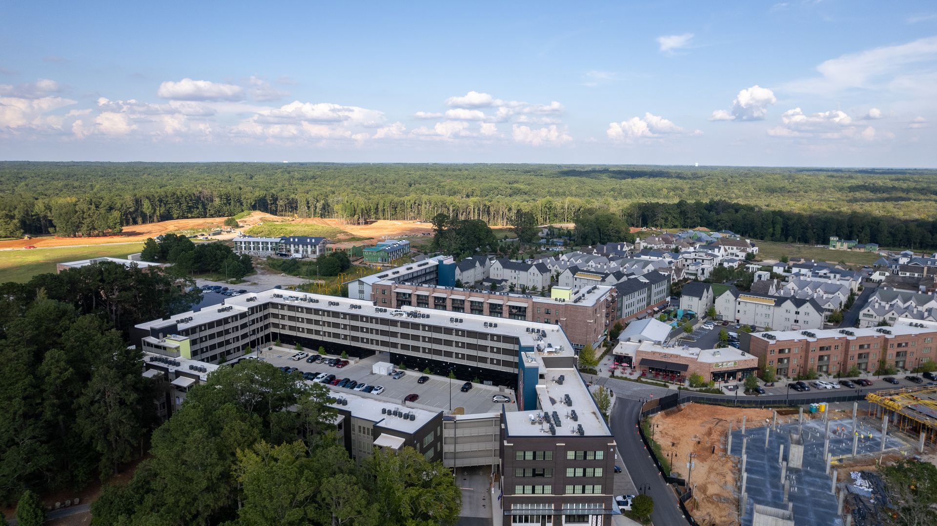 An aerial view of a city with a lot of buildings and trees in the background.