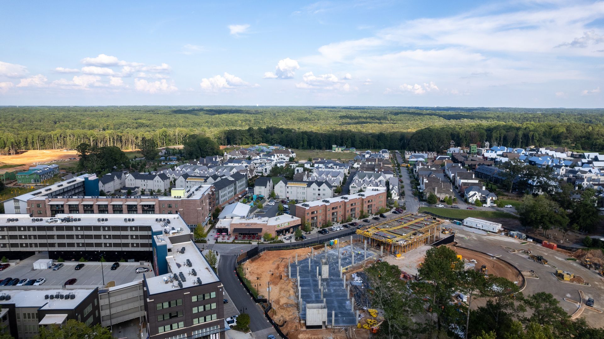 An aerial view of a city with a lot of buildings and trees in the background.