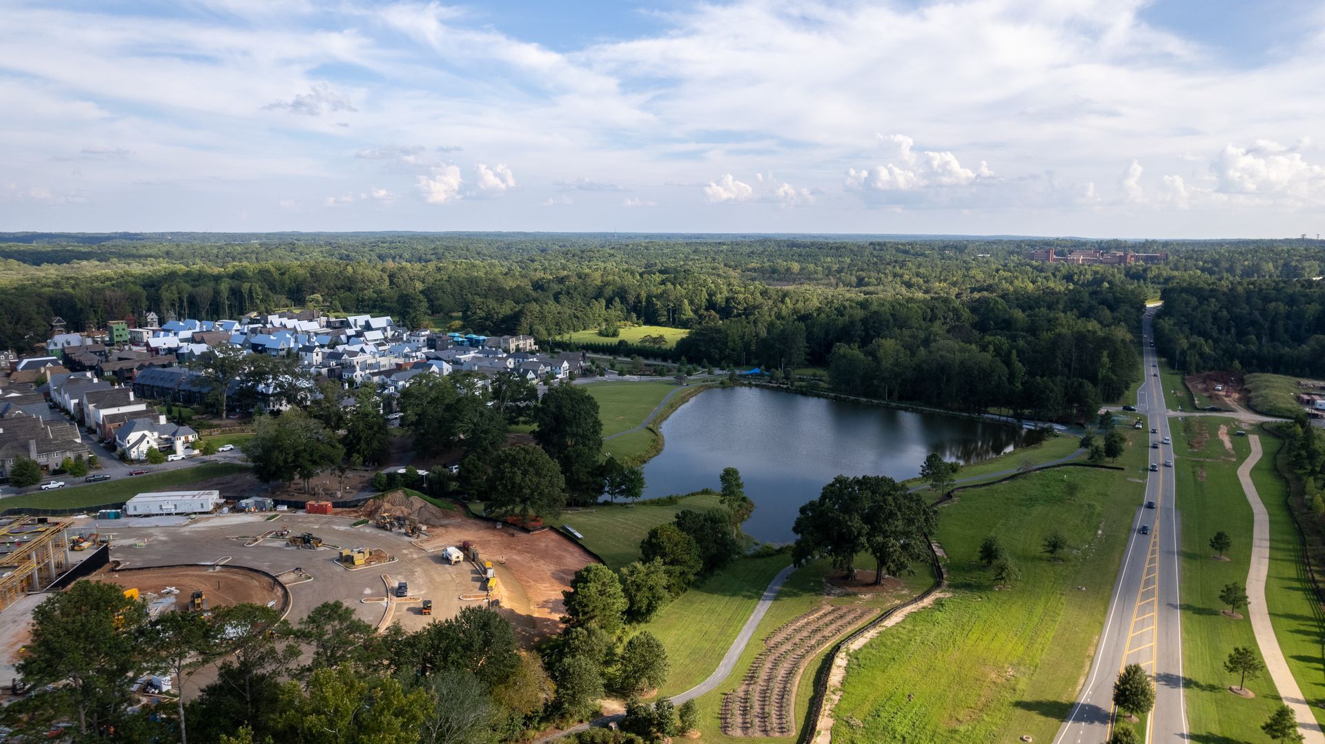 An aerial view of a lake surrounded by trees and a road.