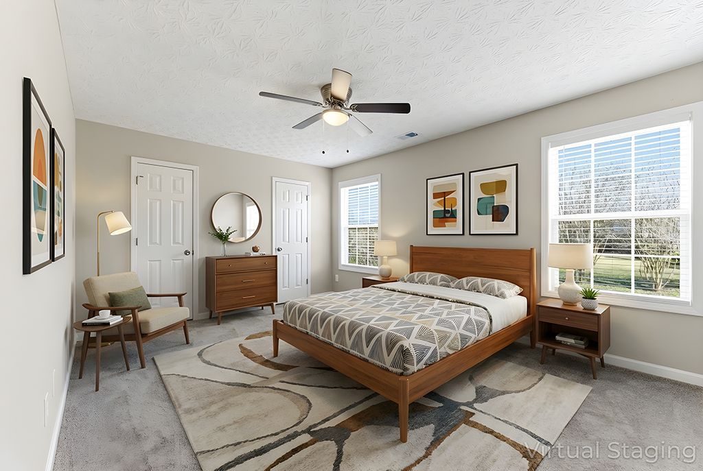 Bedroom with bed, dresser, chair, rug, artwork, and windows.