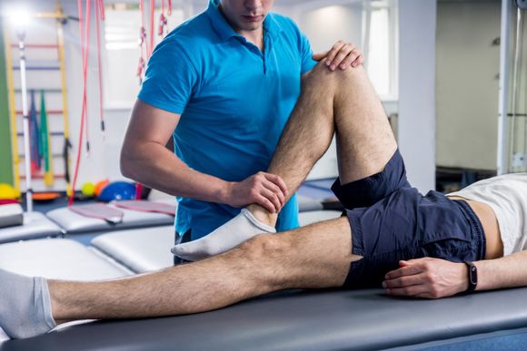 A man is getting a knee massage from a physical therapist in a gym.