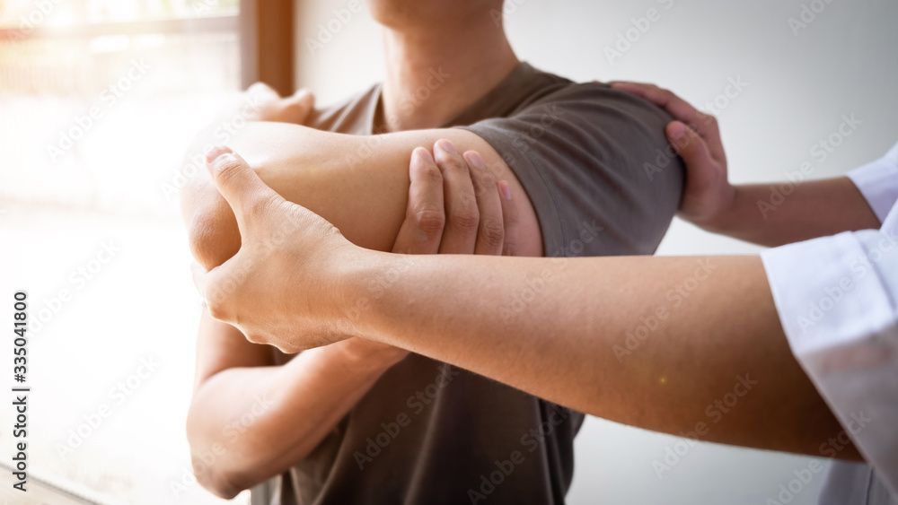 A man is getting his shoulder examined by a doctor.