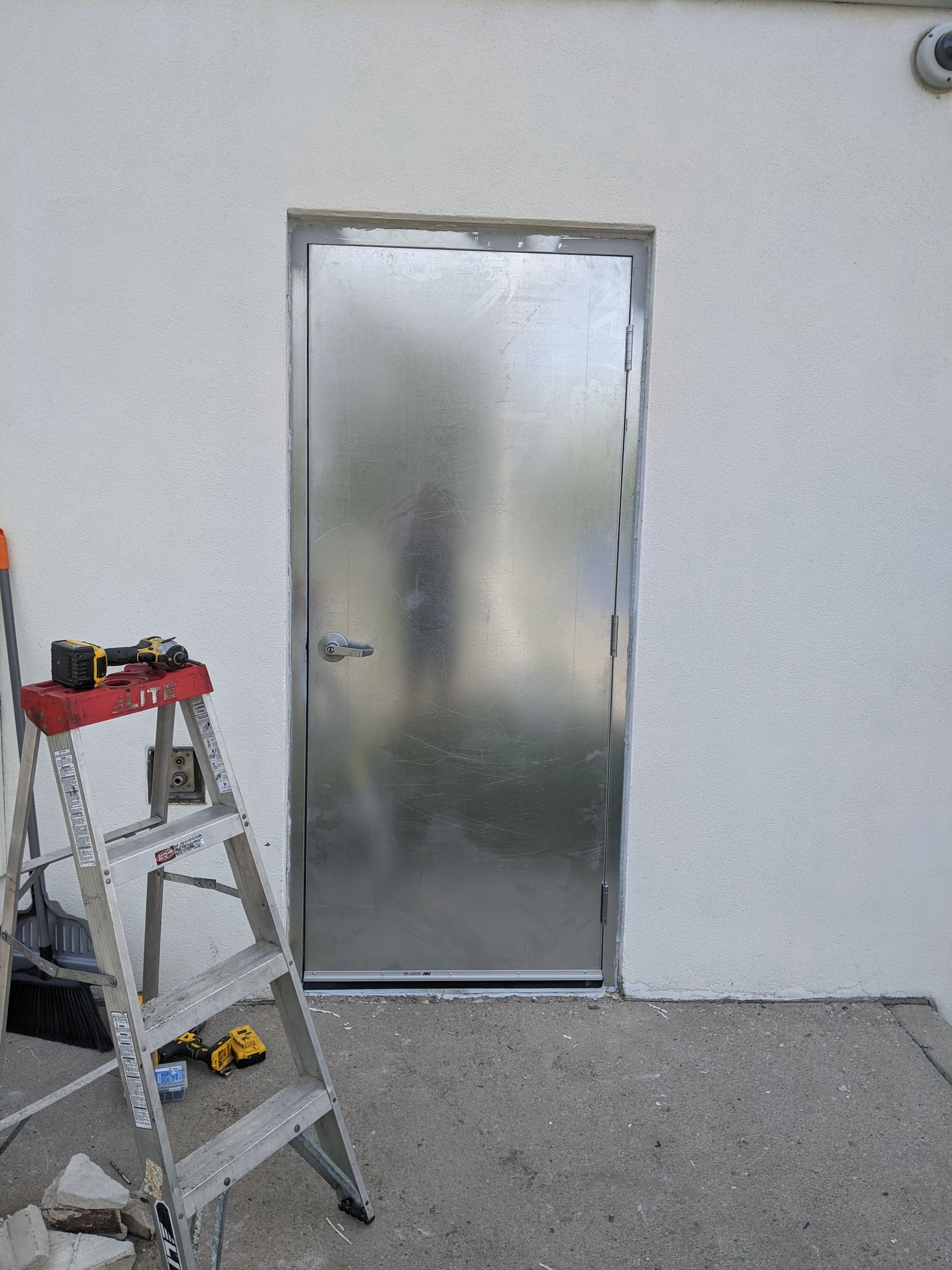 A ladder is sitting in front of a metal door.