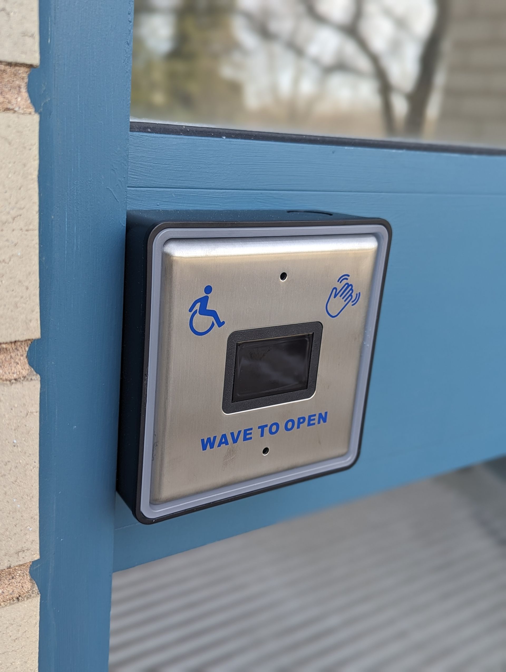A button on a door that says wave to open