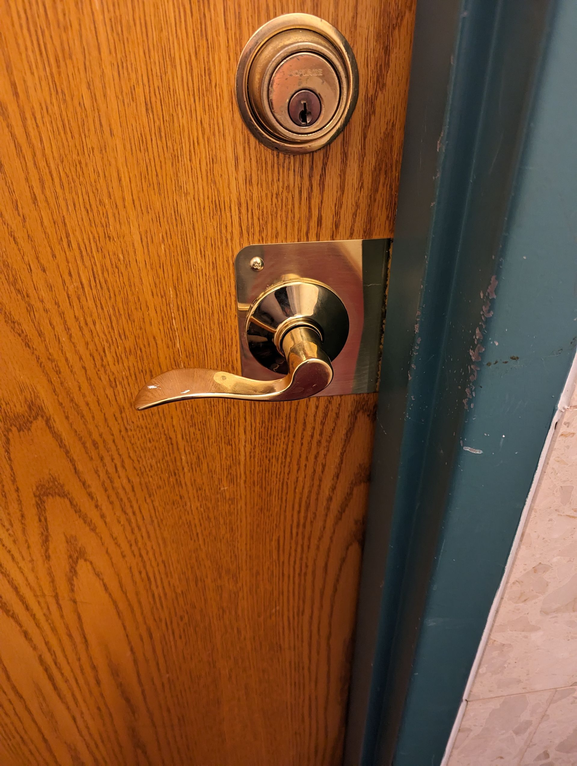 A close up of a door lock on a wooden door.