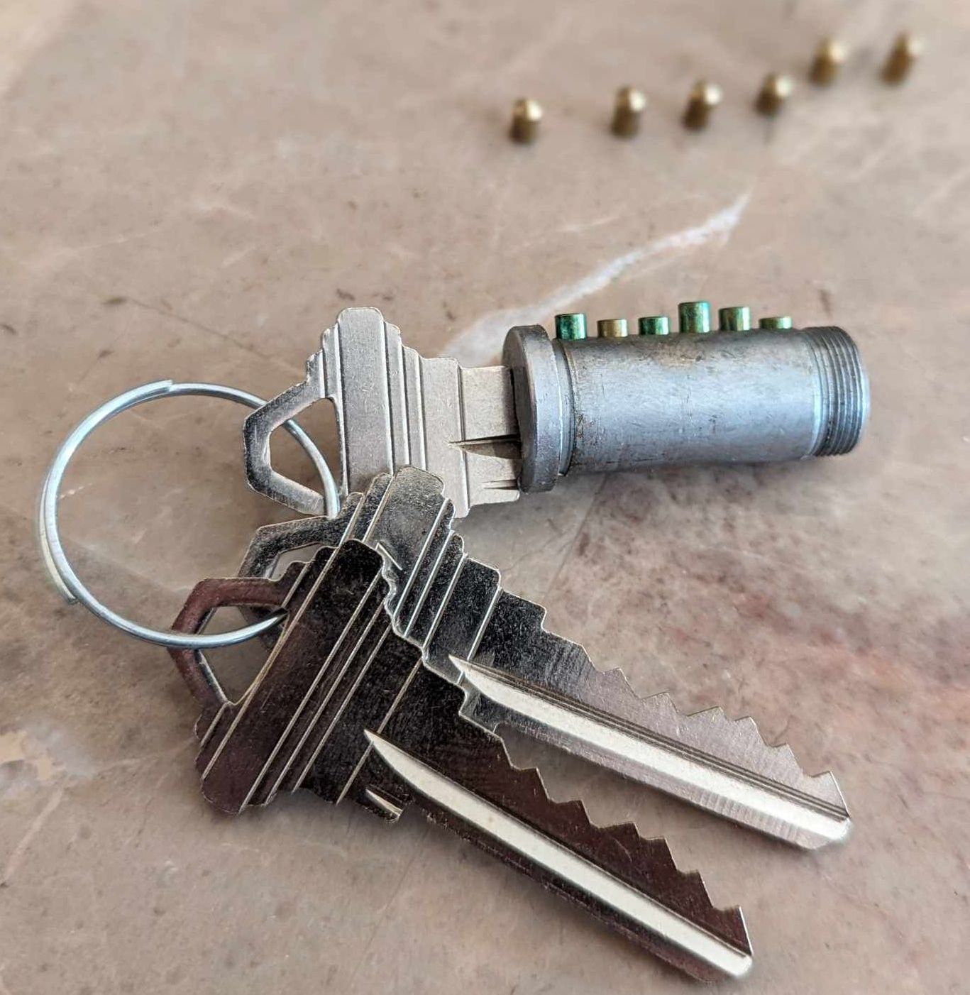 Technician using tools to repair a silver door lock and latch.