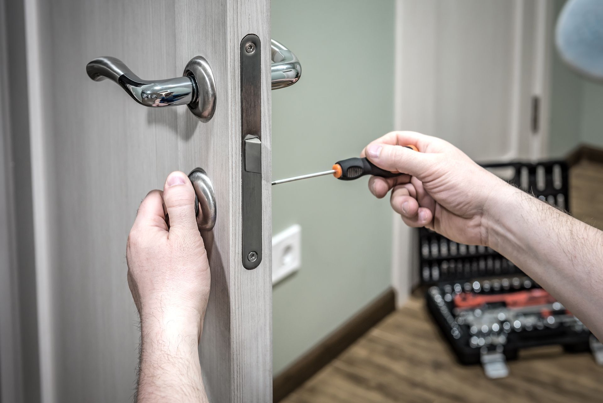 A person is fixing a door with a screwdriver.