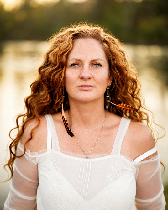 Dr. Sky Asher outdoors beside weathered stone