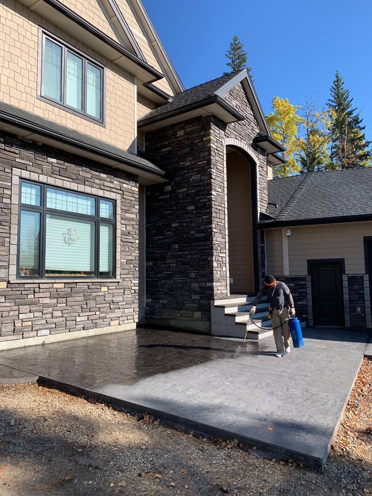Two people entering a modern brick house with a covered front porch on a sunny day
