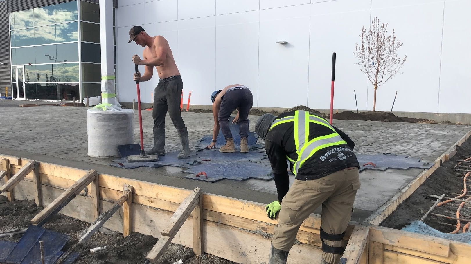 Workers pouring concrete on a foundation slab at a construction site