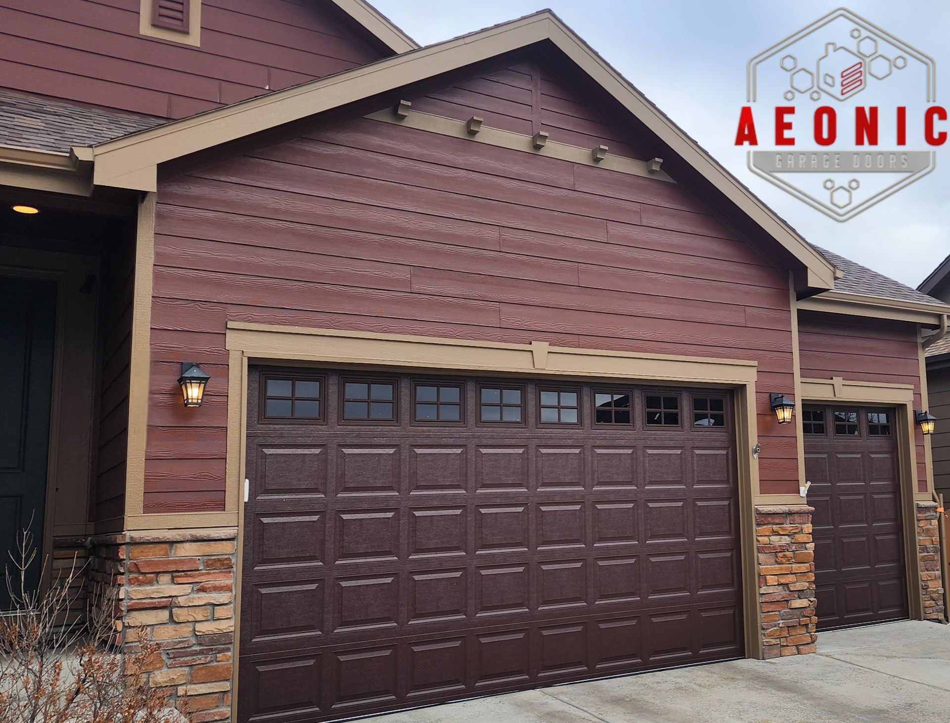 Brown double garage door on a brick townhouse exterior with a side entry door and driveway.