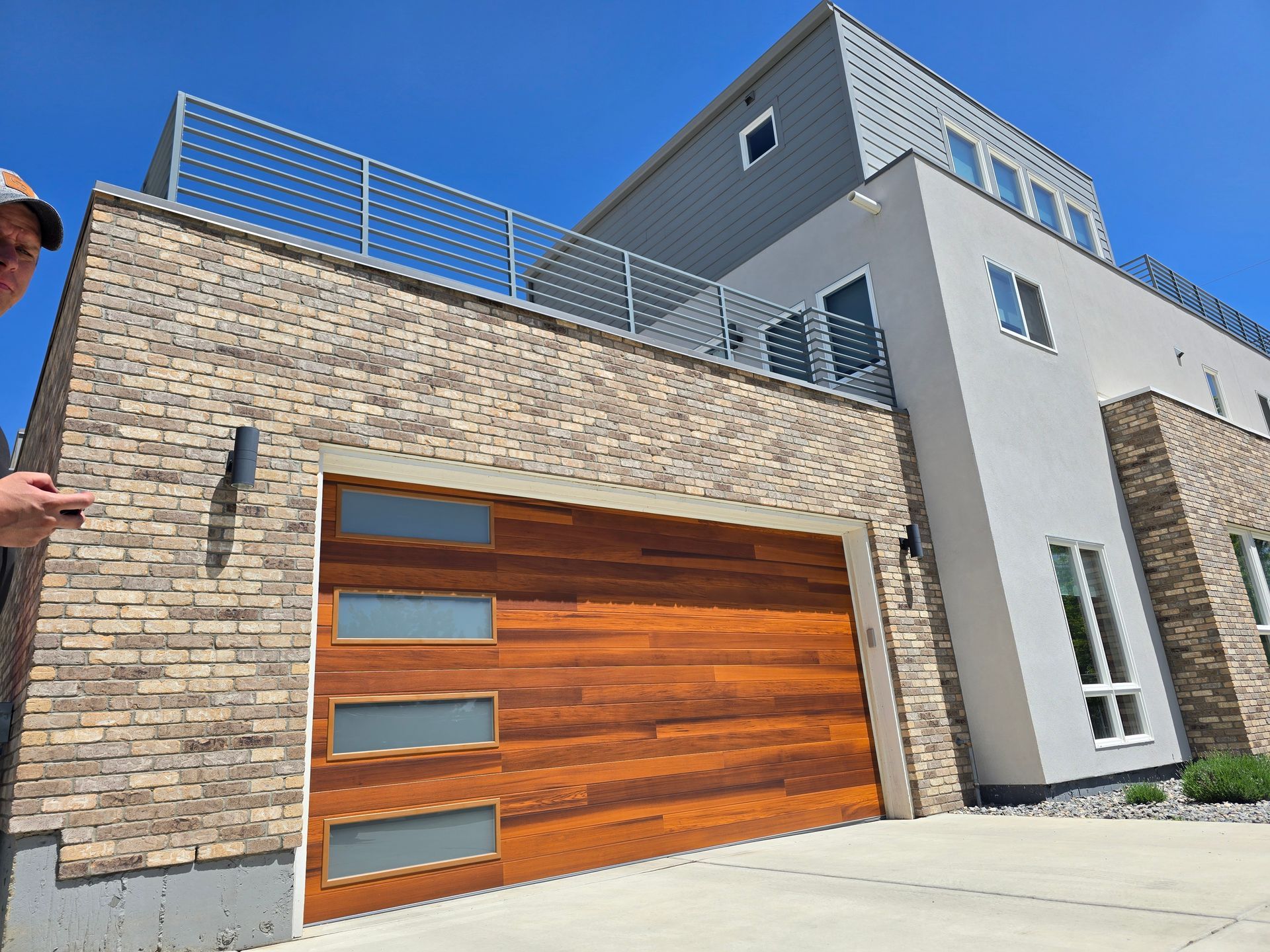 Modern house exterior with brick and wood garage door under a blue sky