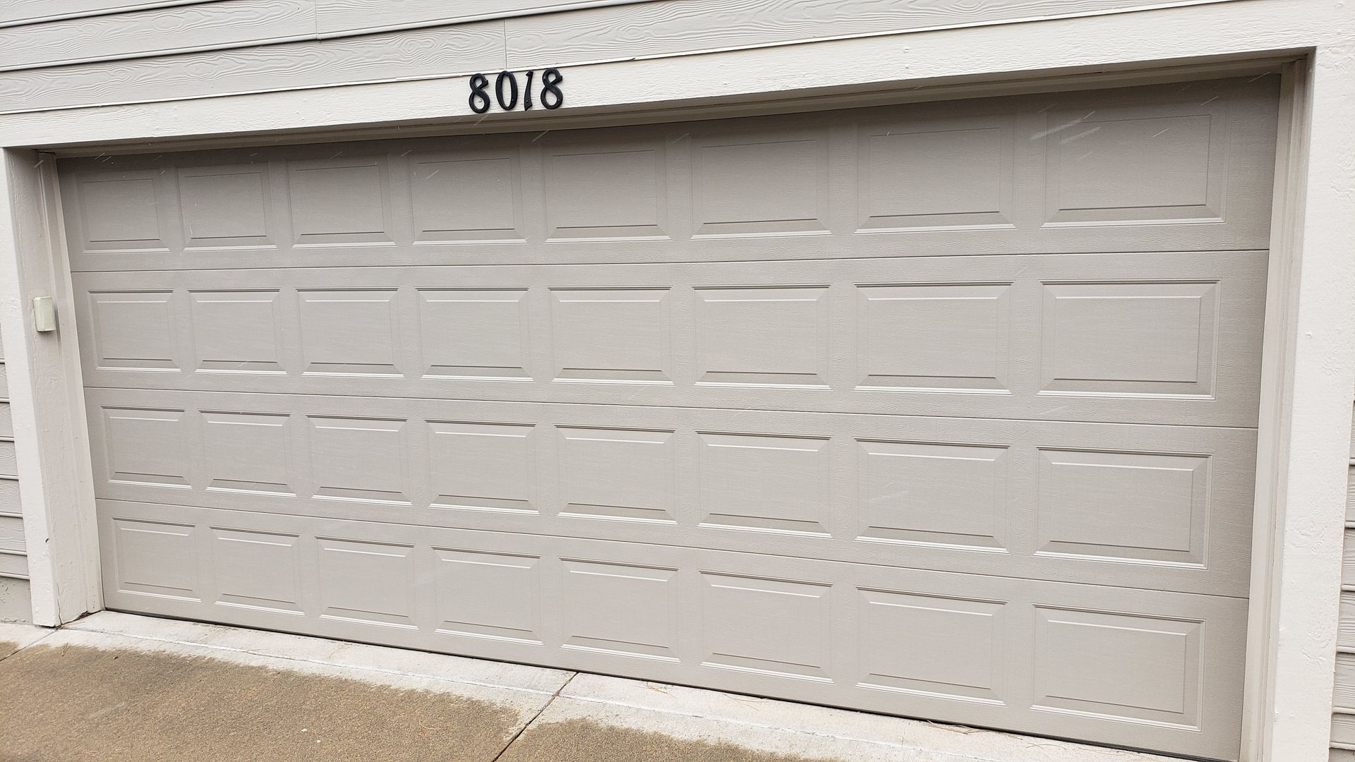 Closed white garage door with the house number 8018 above it