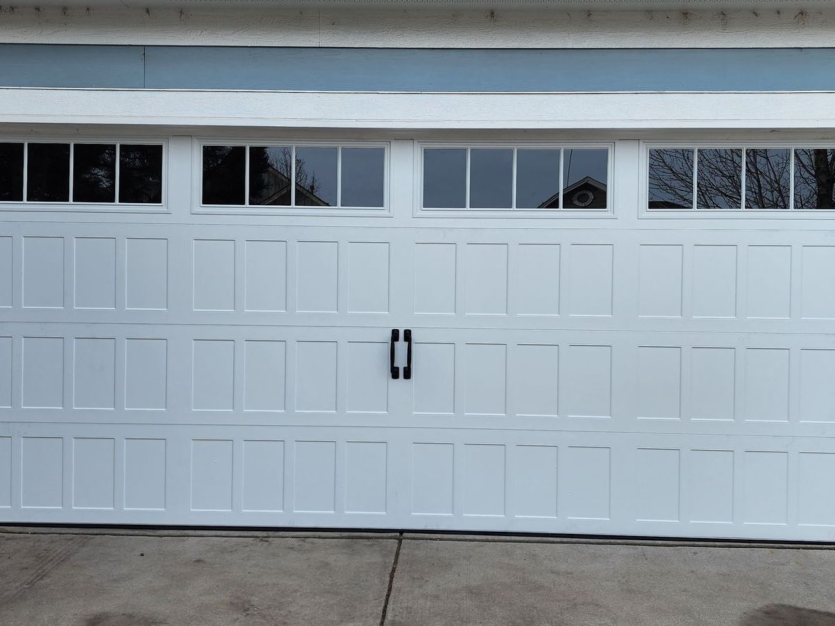White two-car garage door with small windows and a black handle