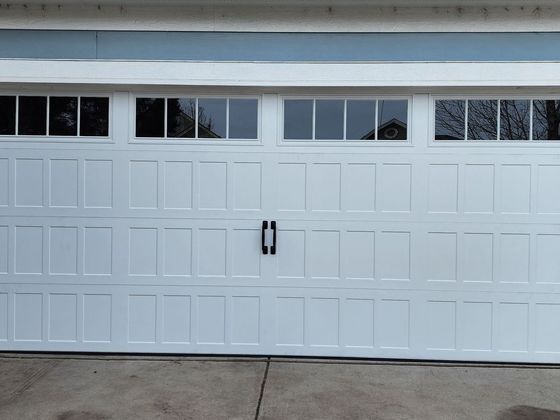 White two-car garage door with small windows and a black handle