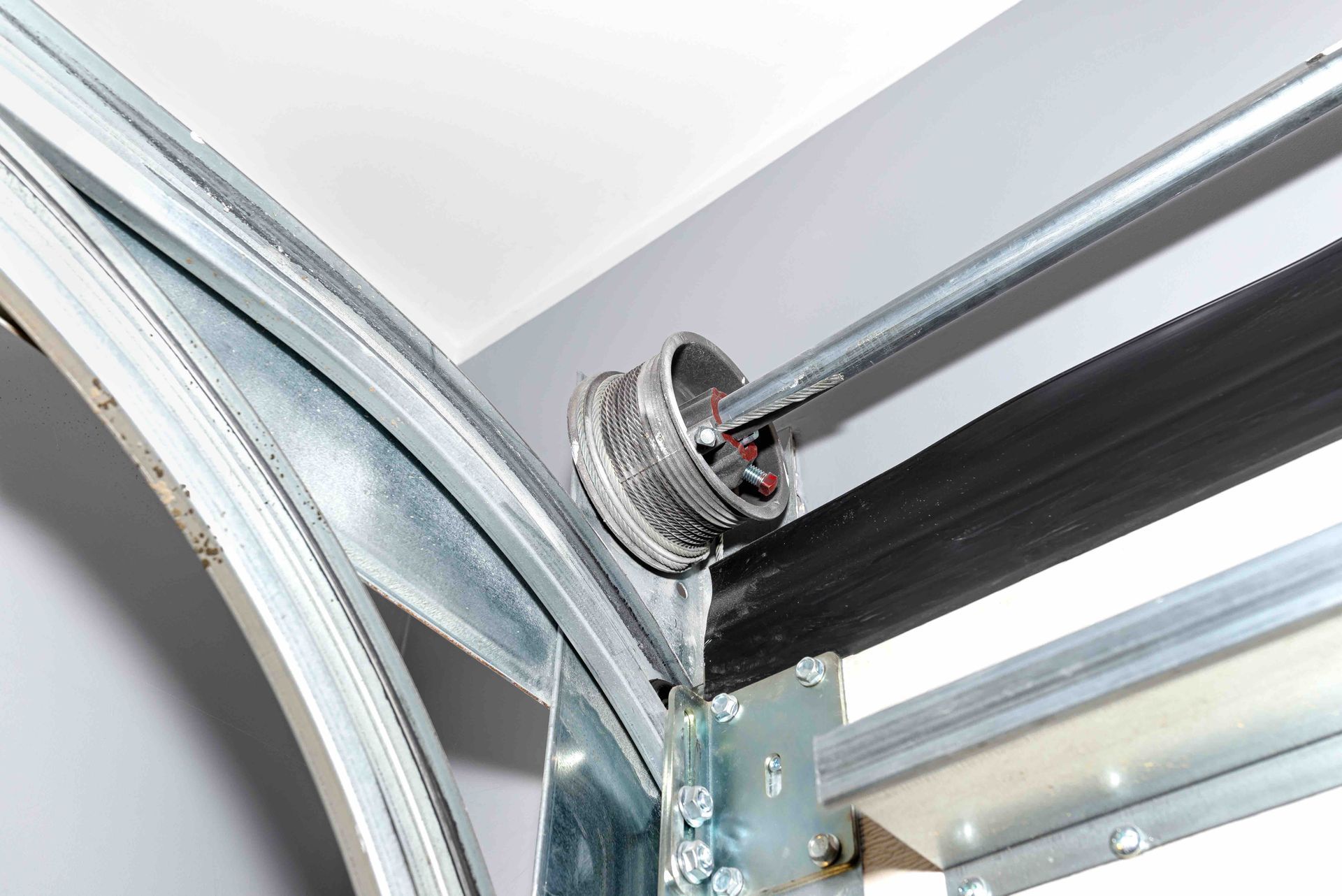 Close-up of a garage door roller and metal track with black weatherstripping