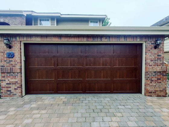 Brick house with a large brown garage door and paved driveway