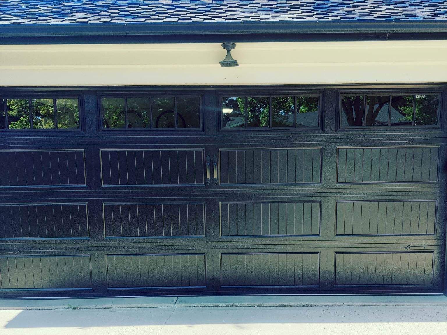 Closed dark blue garage door under a white overhang with small windows above