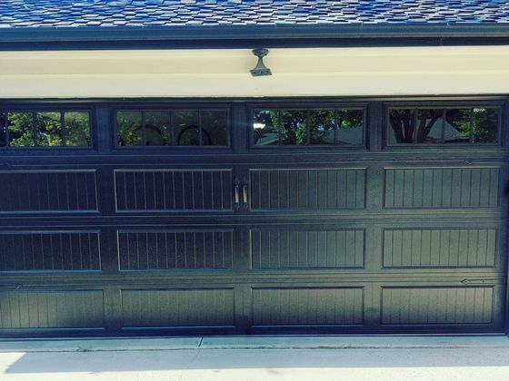 Closed dark blue garage door under a white overhang with small windows above