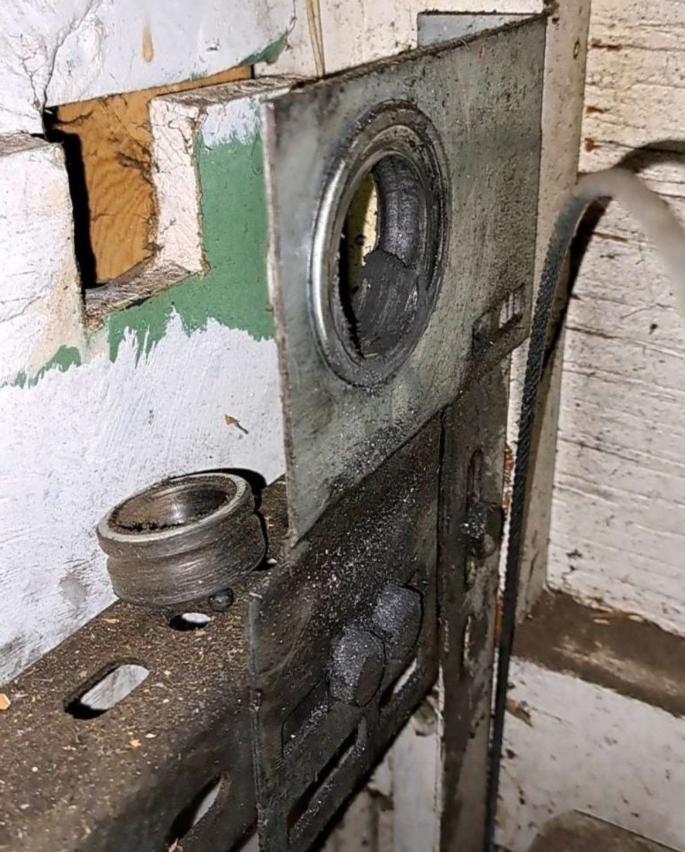 Close-up of a damaged metal lock mechanism on a worn wooden door frame.