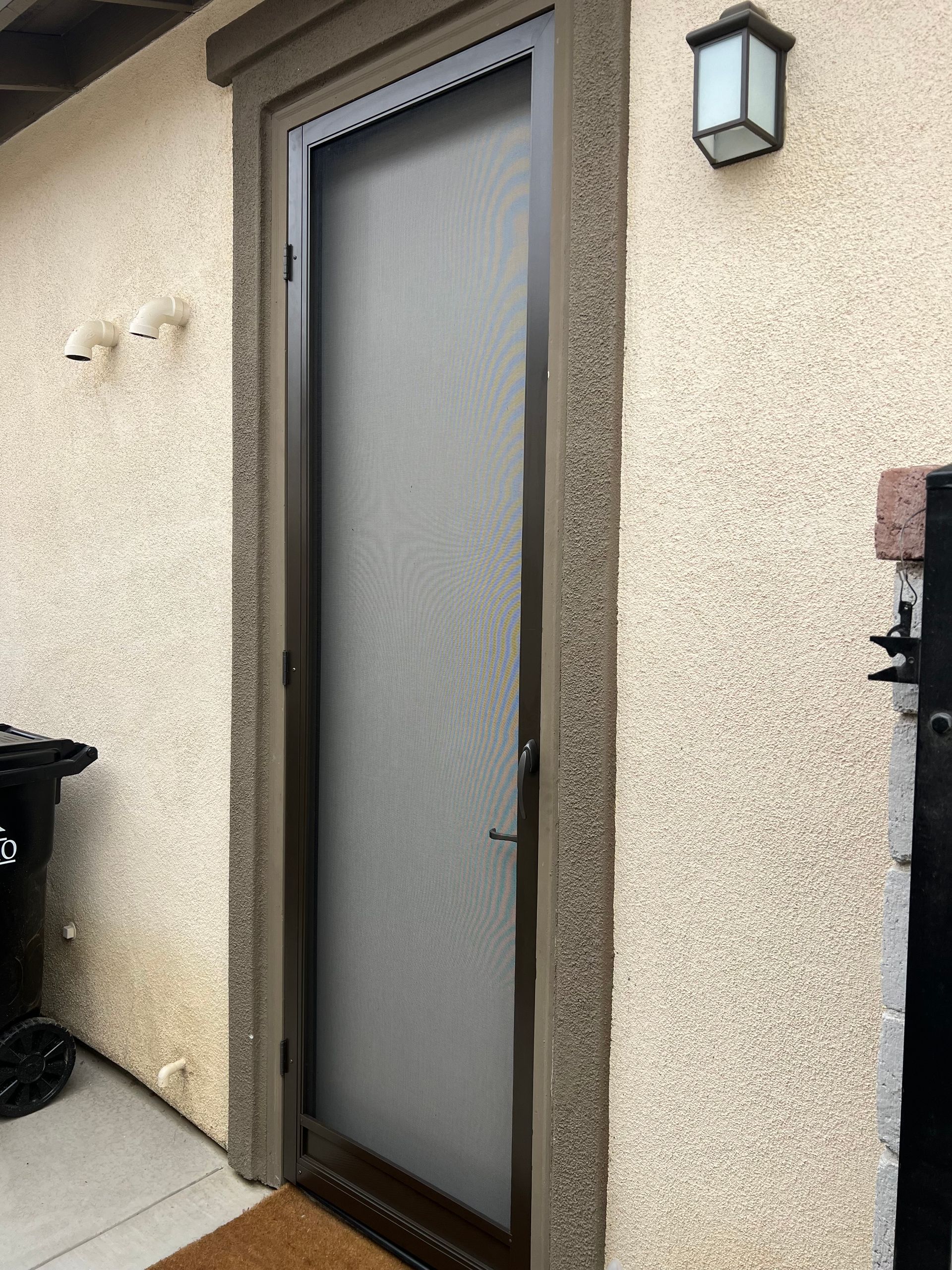 Exterior side door with a fitted screen door on a stucco wall