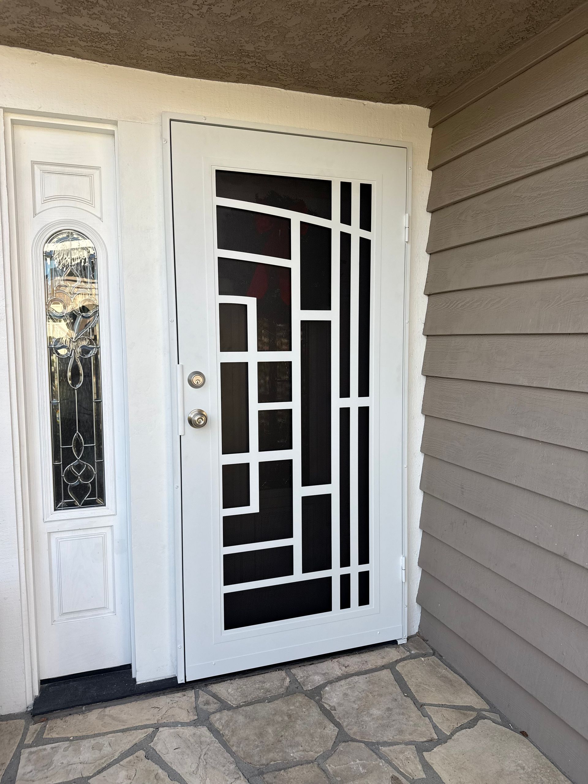 White front entry door with decorative glass and a screen door installed