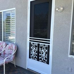 White  swinging screen door installed on side door with small bench next to the door and under the window.
