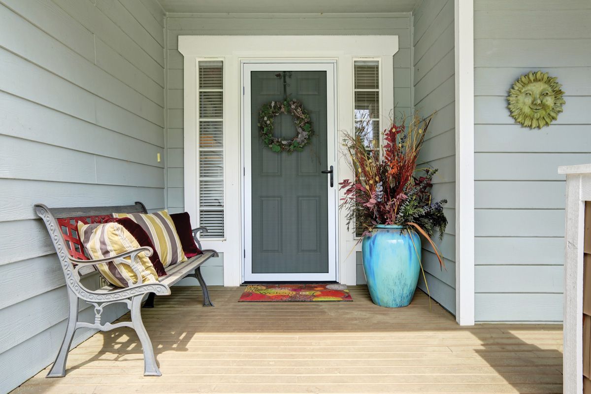 Front porch with a white entry screen door and decorative wreath
