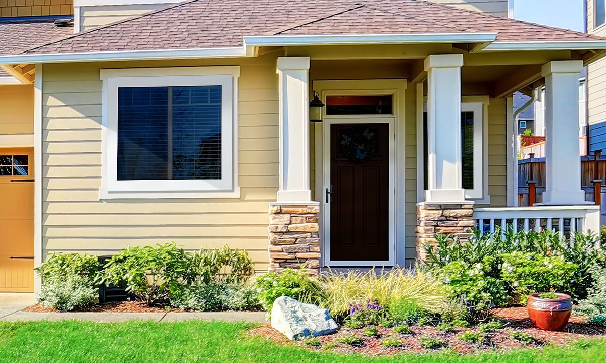 Front of a home with landscaped yard and screened entry door
