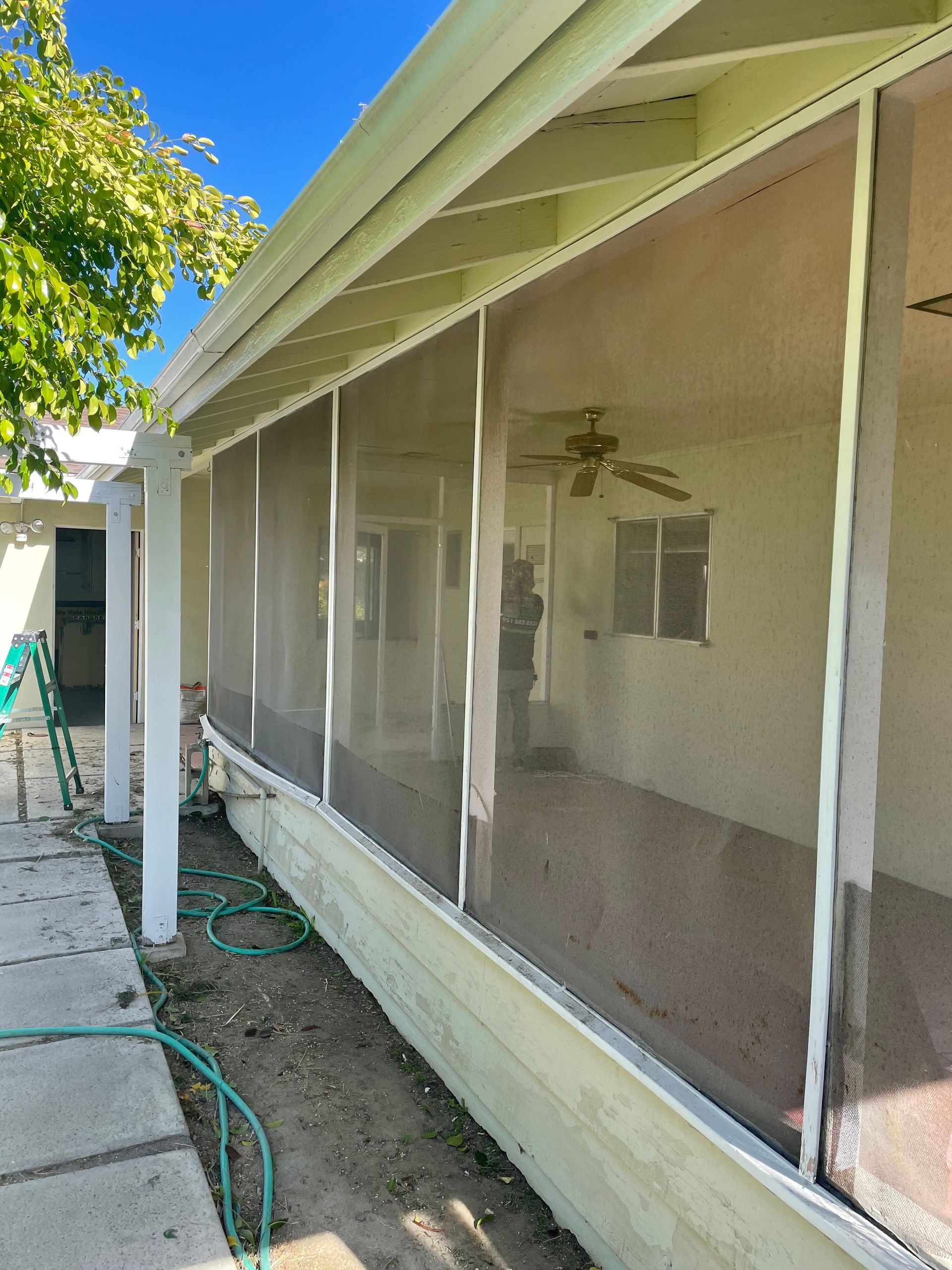 Long screened patio enclosure covering multiple windows along a house