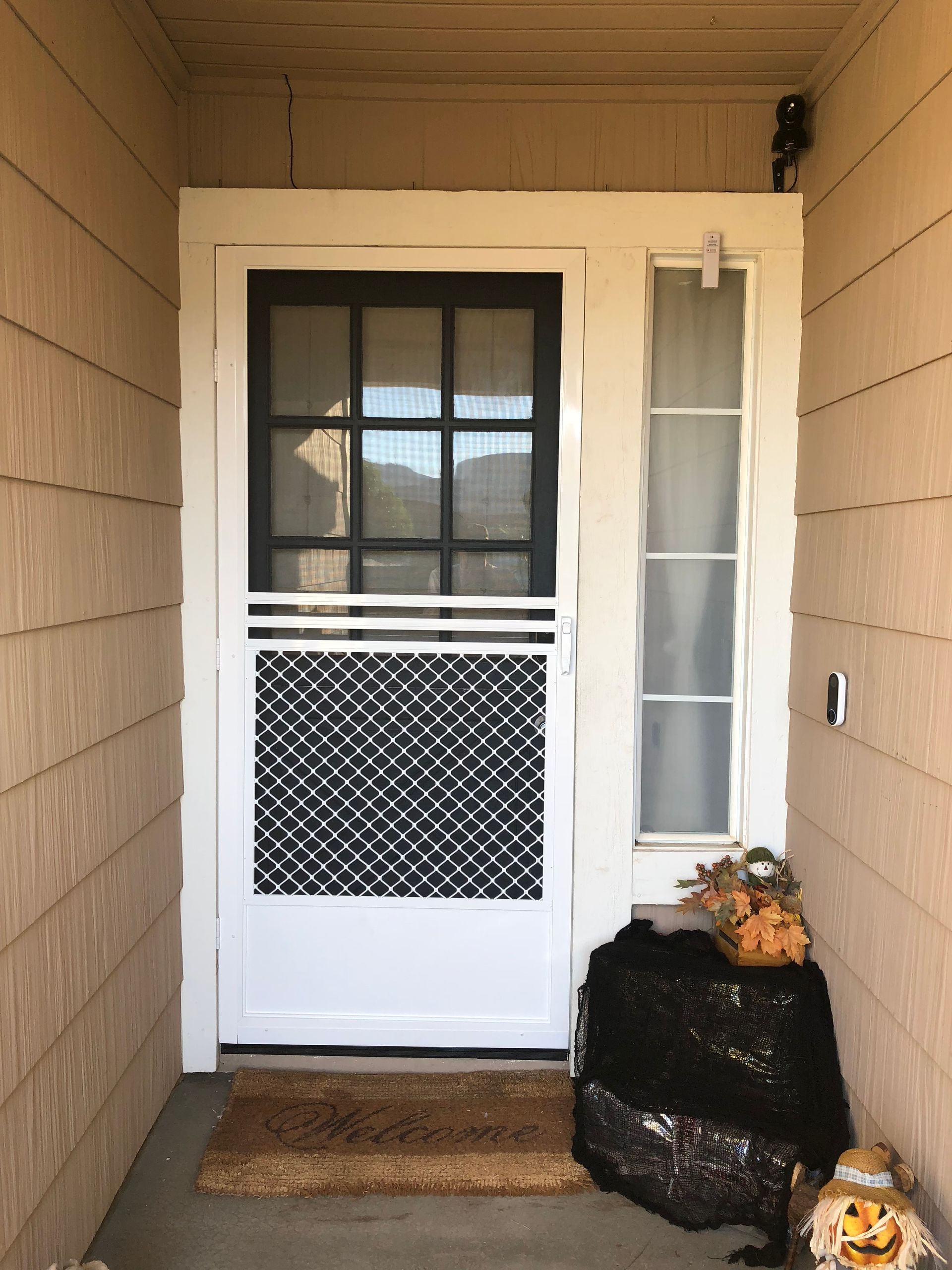 Front door with a white security screen door featuring a lower mesh panel