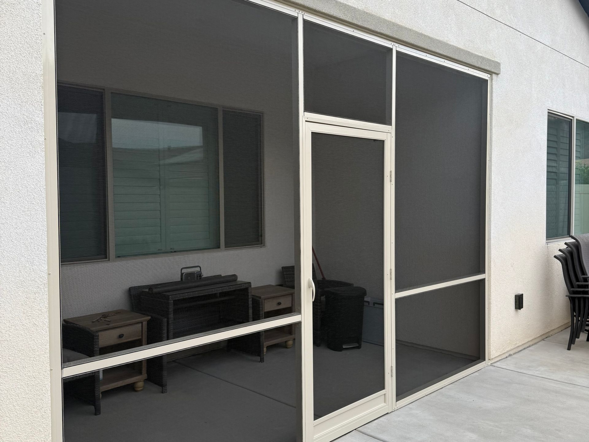 Screened patio enclosure with sliding screen doors and outdoor seating