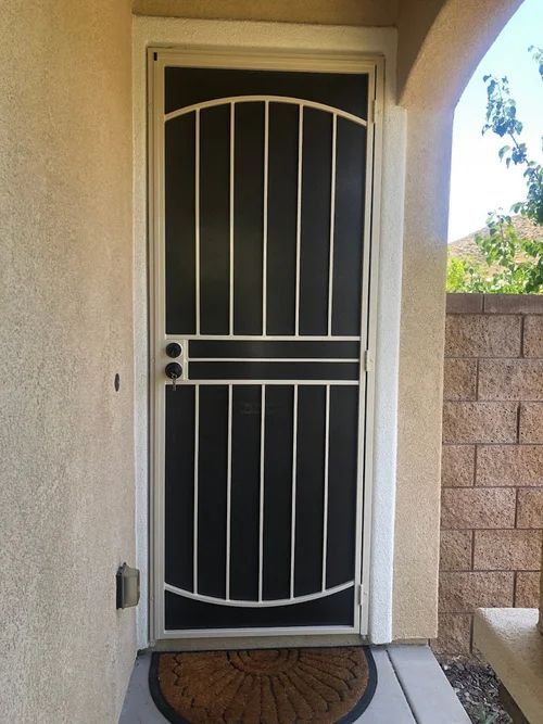 Arched entry with a black security screen door and vertical bars
