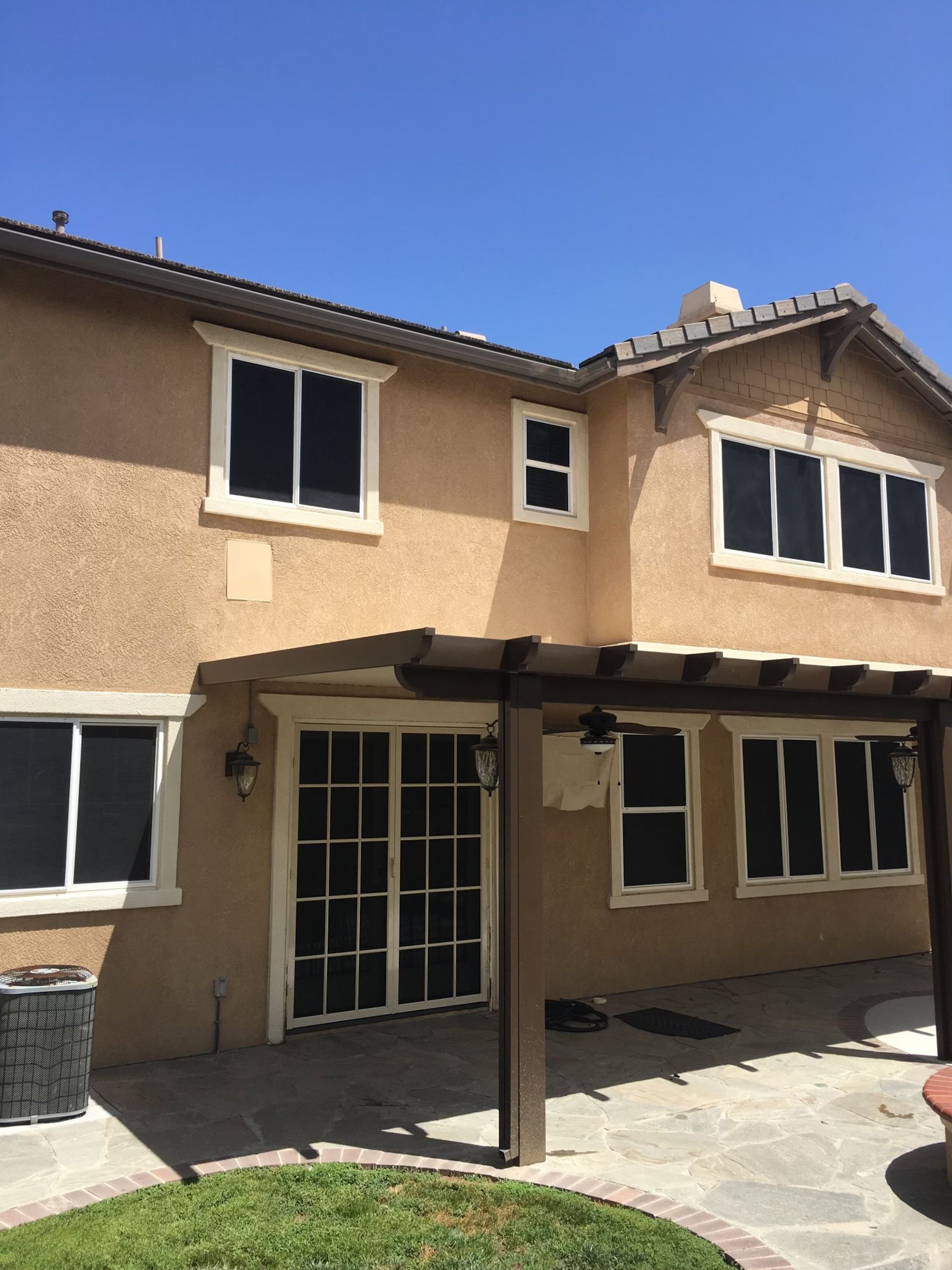 Back of a two-story house with screened windows and a covered patio