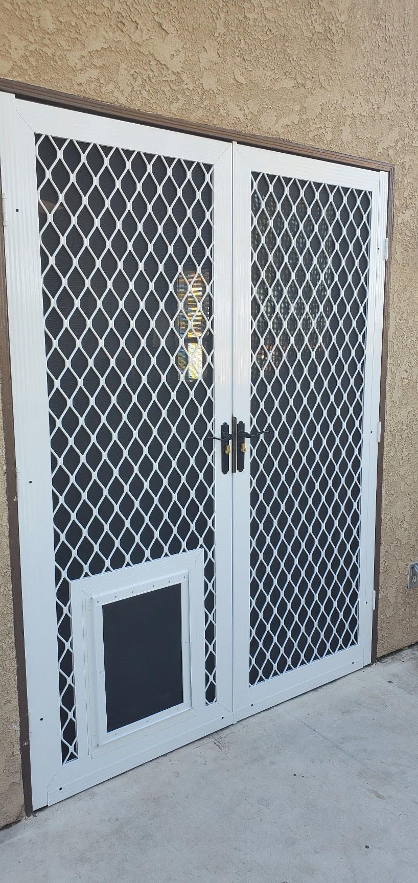 Double doors with white security screen panels, mesh inserts, and a pet door on the lower area of one door side.