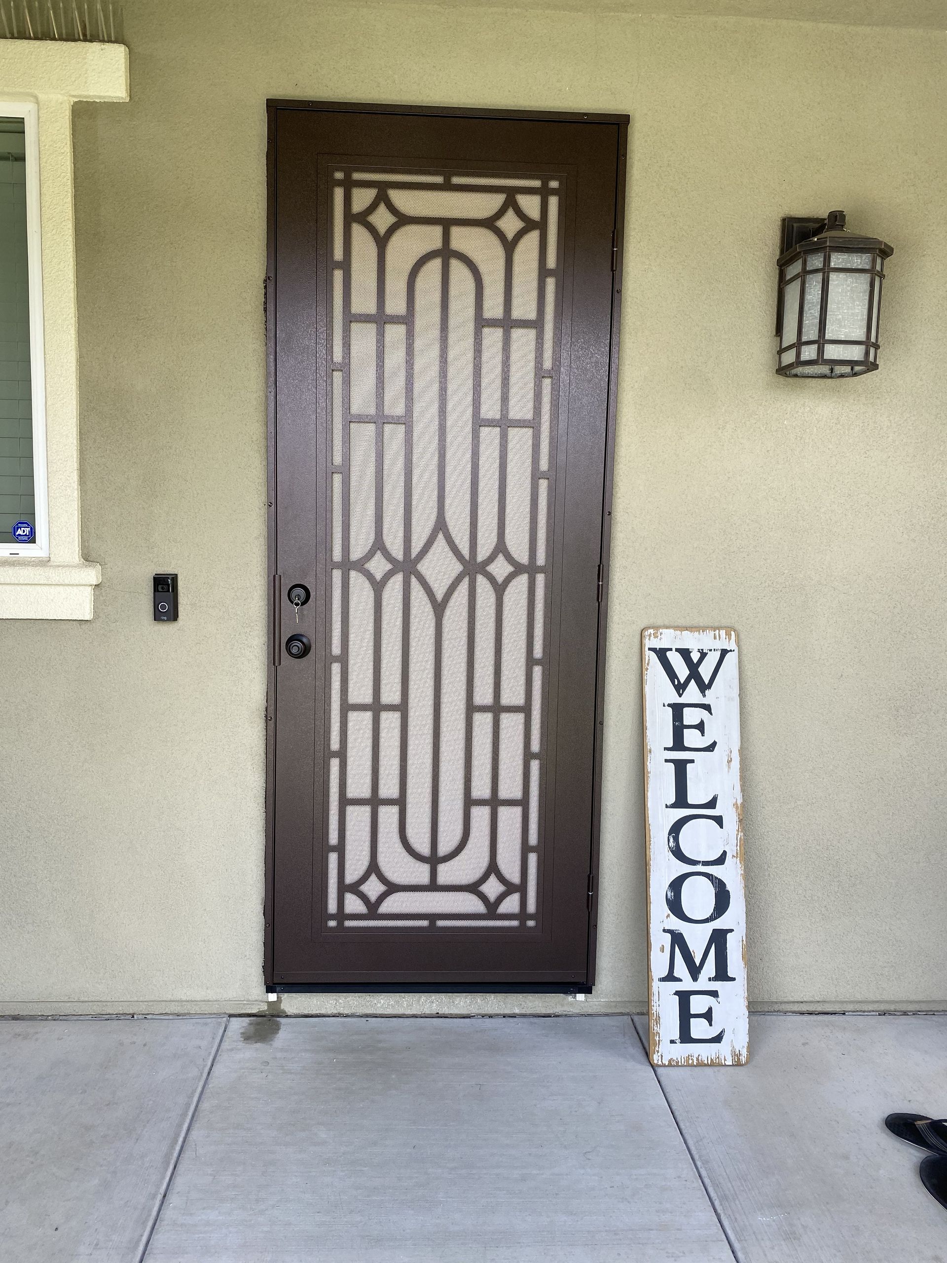 Front entry with a decorative metal security screen door and welcome sign