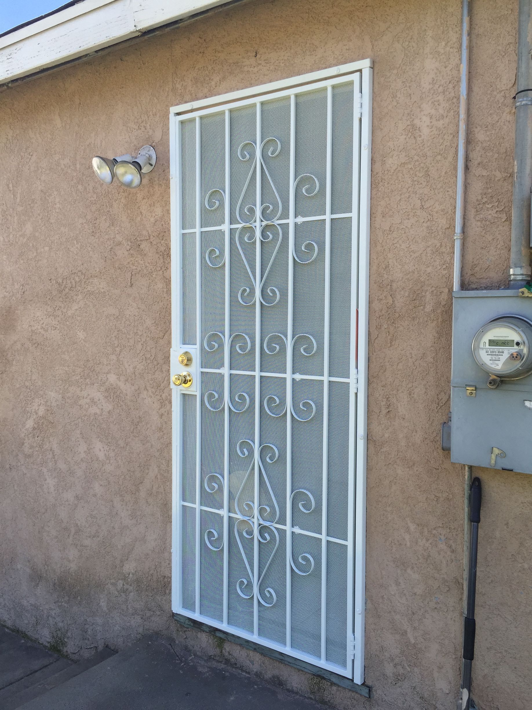 Side exterior door with a white metal security screen door installed
