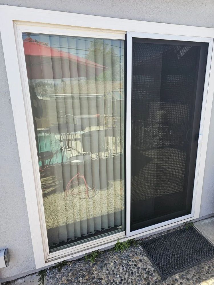 Sliding glass door with a screen door and vertical blinds inside