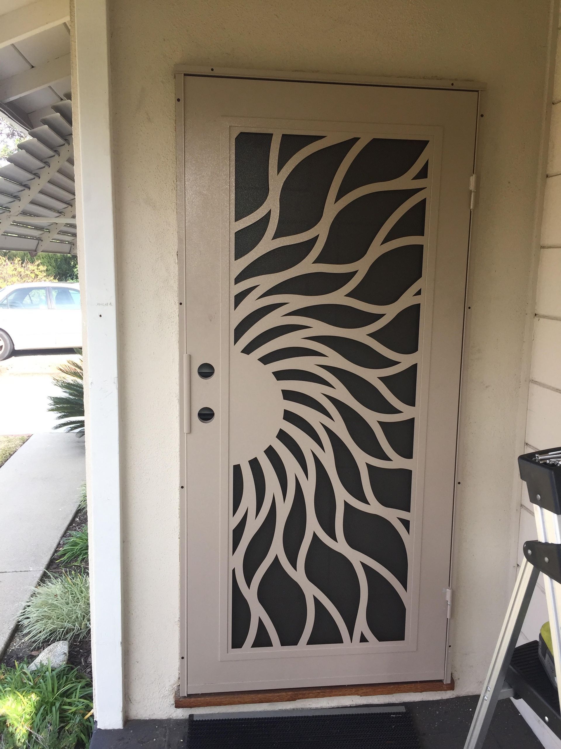 Front door with a dark security screen featuring a sunburst pattern