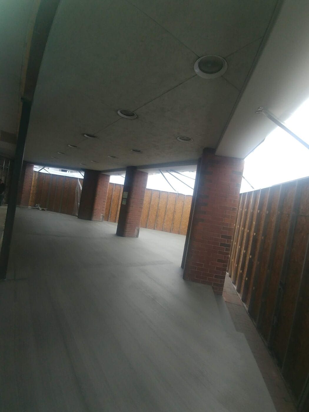 An empty hallway with brick columns and a wooden fence