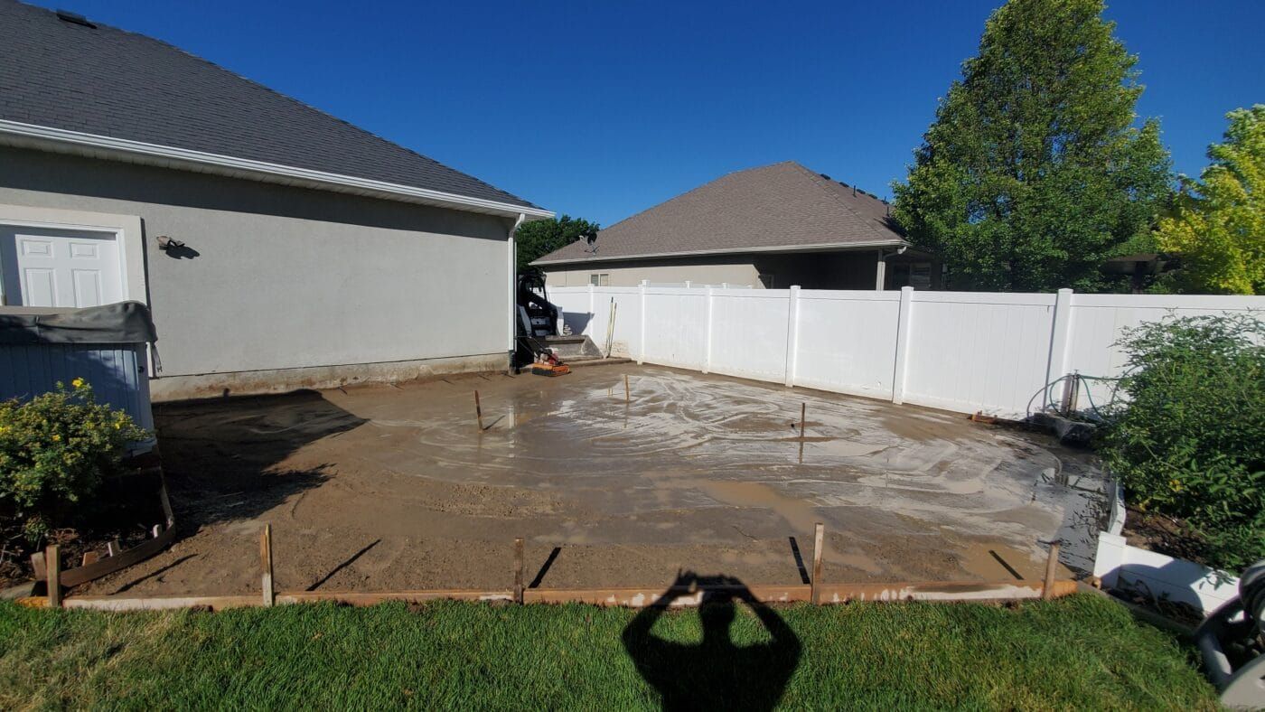 A man is taking a picture of a concrete driveway in front of a house.