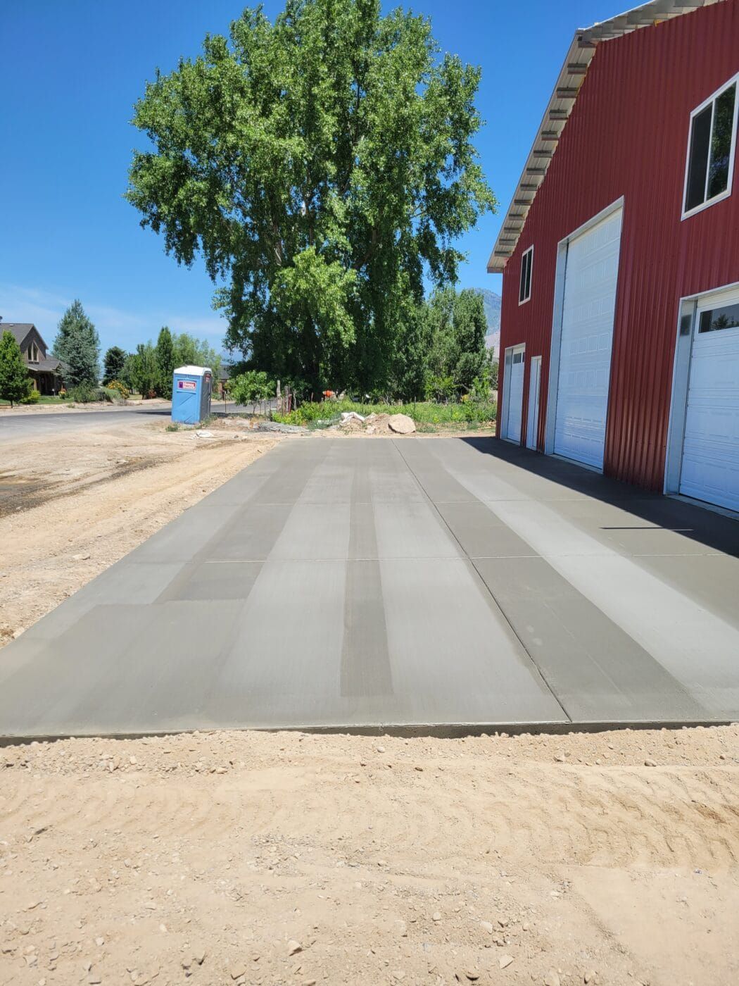 A concrete driveway with a red barn in the background
