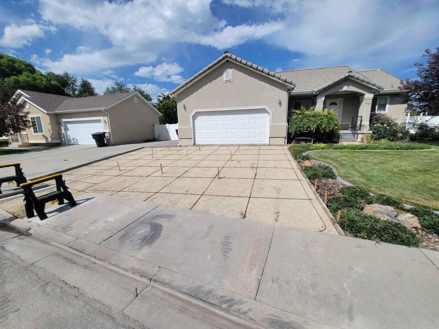 A house with two garage doors and a concrete driveway in front of it.
