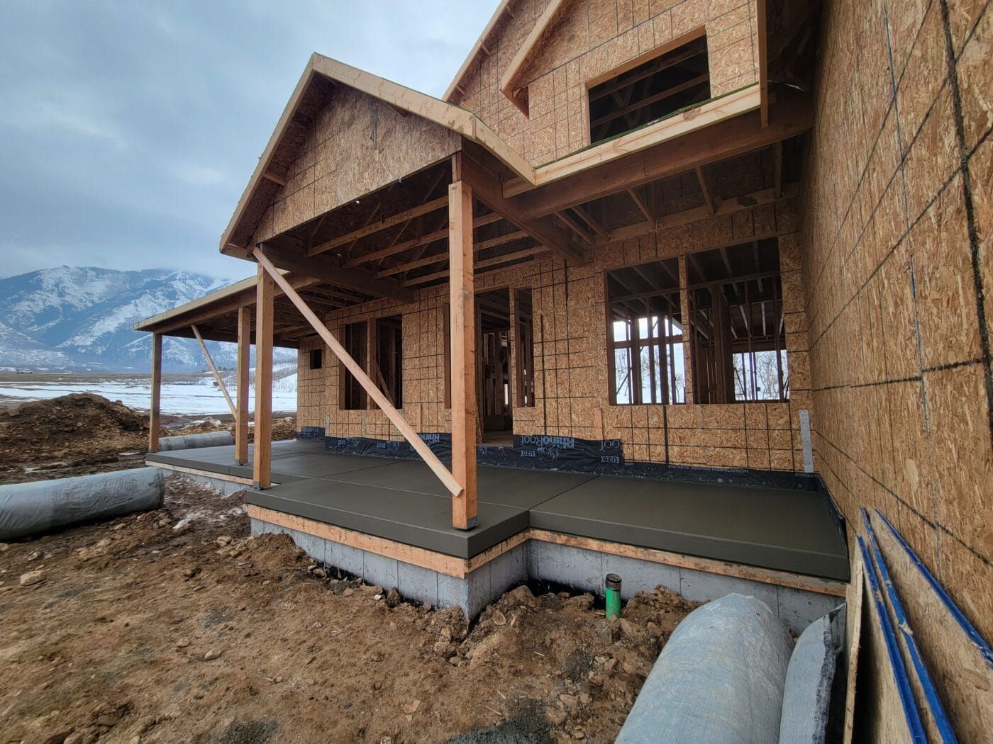 A house is being built with a porch and mountains in the background.